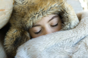 Preteen girl, wearing fur hat, sleeping under fur blanket, close-up