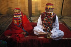 A bride and groom sit together during a mass marriage ceremony held in Karachi